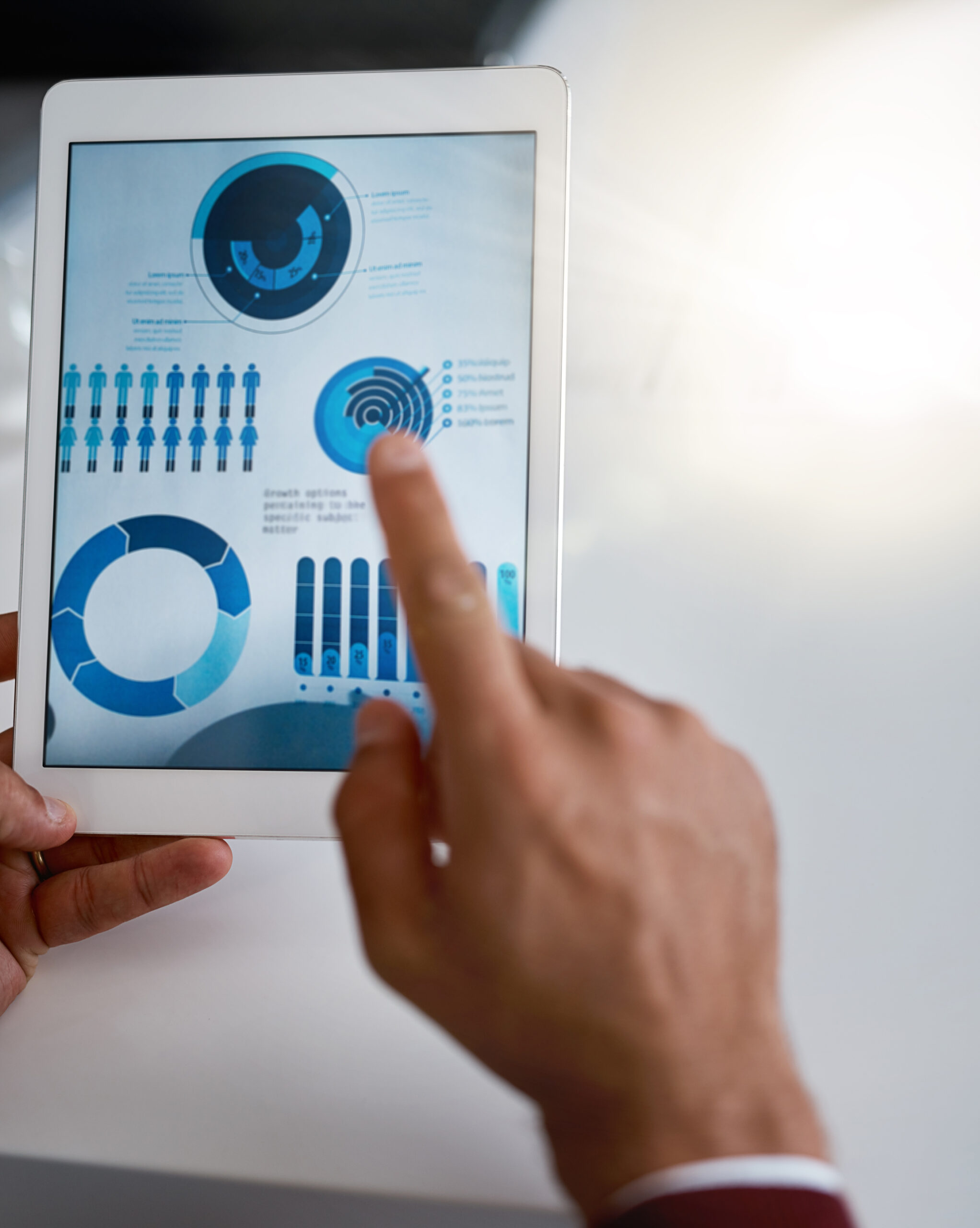 Rearview shot of an unrecognizable businessmen looking at charts and graphs on his tablet in the office.